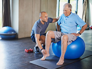 An old man sitting on an exercise receiving physical therapy